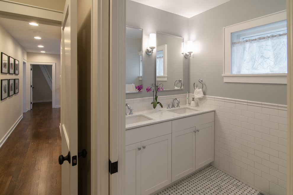 Medium sized bohemian bathroom in Seattle with raised-panel cabinets, white cabinets, an alcove shower, a one-piece toilet, white tiles, metro tiles, grey walls, mosaic tile flooring, a submerged sink, solid surface worktops, white floors, a hinged door and white worktops.