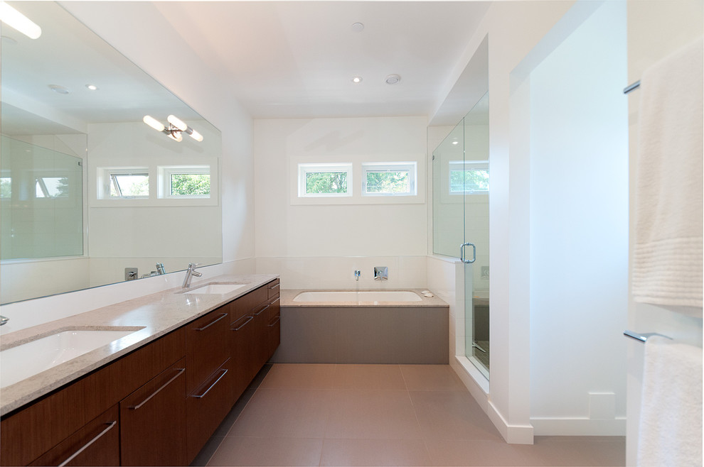 Immagine di una stanza da bagno design con lavabo sottopiano, ante lisce, ante in legno bruno e vasca sottopiano