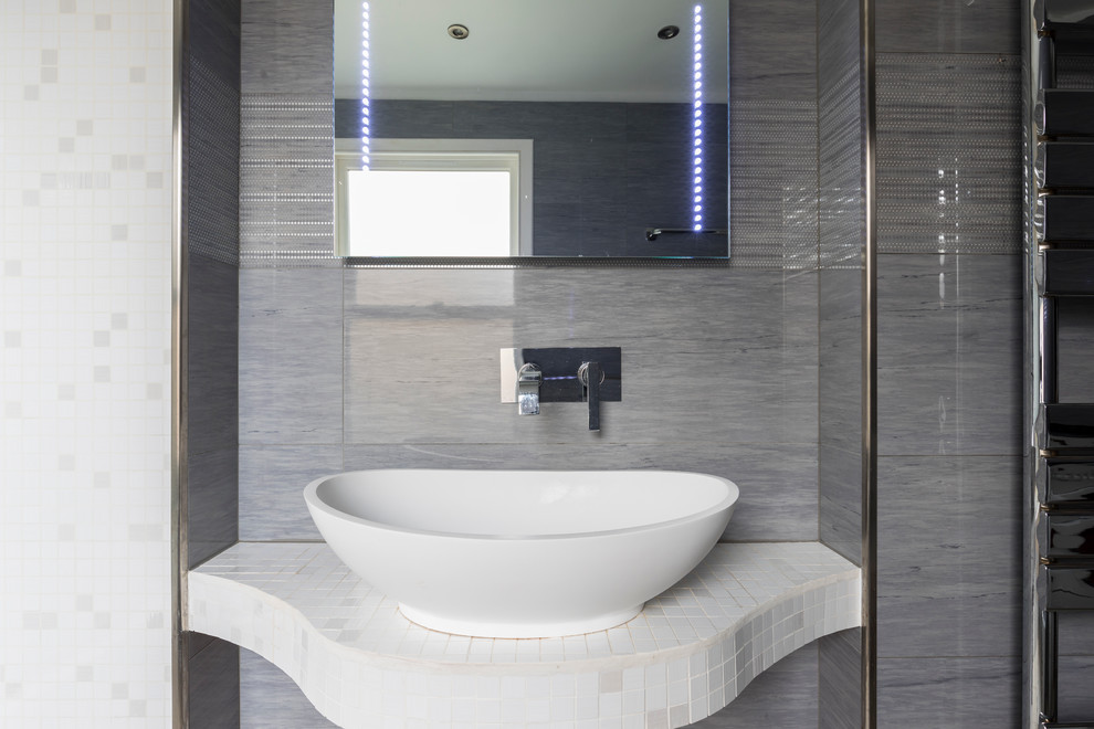 Photo of a medium sized contemporary family bathroom in London with brown cabinets, a freestanding bath, a two-piece toilet, brown tiles, cement tiles, beige walls, a vessel sink, solid surface worktops and light hardwood flooring.
