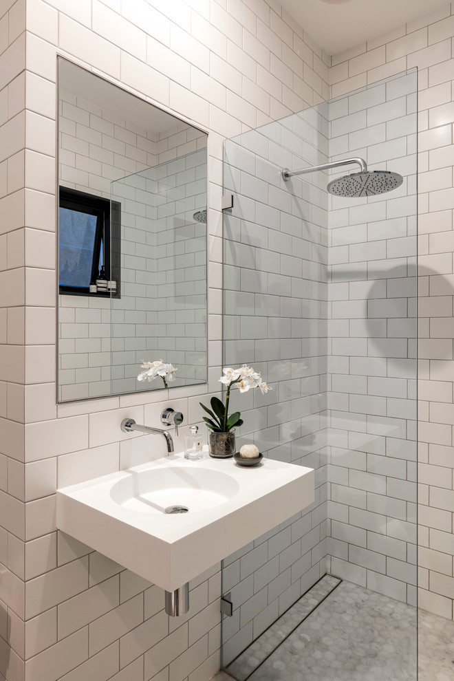 Inspiration för ett litet funkis badrum med dusch, med öppna hyllor, en öppen dusch, en toalettstol med hel cisternkåpa, vit kakel, tunnelbanekakel, vita väggar, marmorgolv, ett väggmonterat handfat och bänkskiva i akrylsten