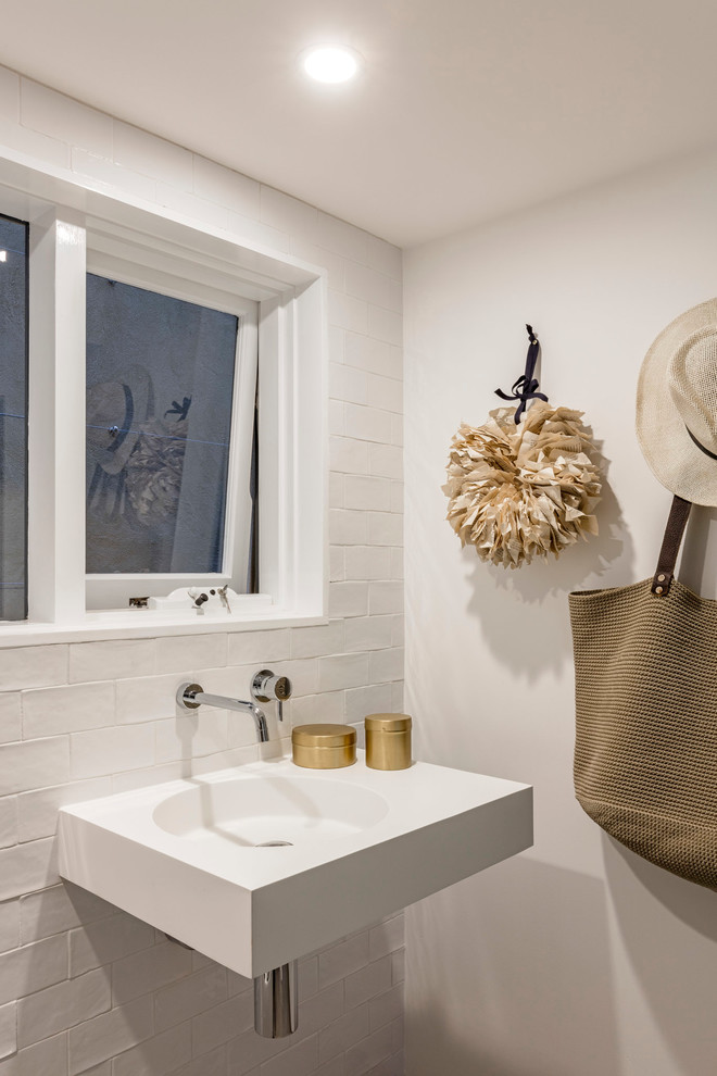 Immagine di una piccola stanza da bagno design con WC monopezzo, piastrelle bianche, piastrelle a mosaico, pareti bianche, pavimento con piastrelle in ceramica e lavabo sospeso
