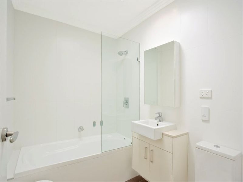 This is an example of a small contemporary ensuite bathroom in Sydney with white cabinets, a wall-mounted sink, recessed-panel cabinets, an alcove bath, a shower/bath combination, a wall mounted toilet, white tiles, ceramic tiles, white walls, porcelain flooring and quartz worktops.