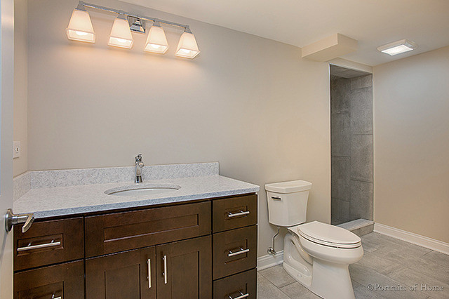 Diseño de cuarto de baño tradicional renovado con armarios estilo shaker, puertas de armario de madera oscura, sanitario de dos piezas, baldosas y/o azulejos grises, paredes beige, lavabo bajoencimera y suelo gris