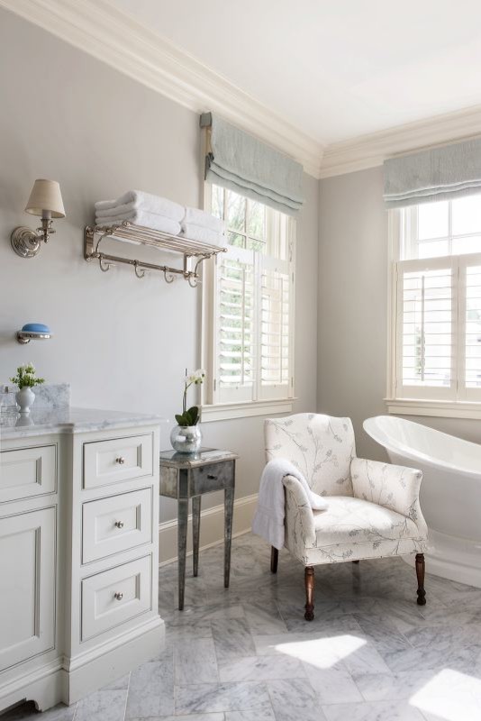 На фото: главная ванная комната в классическом стиле с фасадами с утопленной филенкой, белыми фасадами, отдельно стоящей ванной, серой плиткой, серыми стенами и мраморным полом