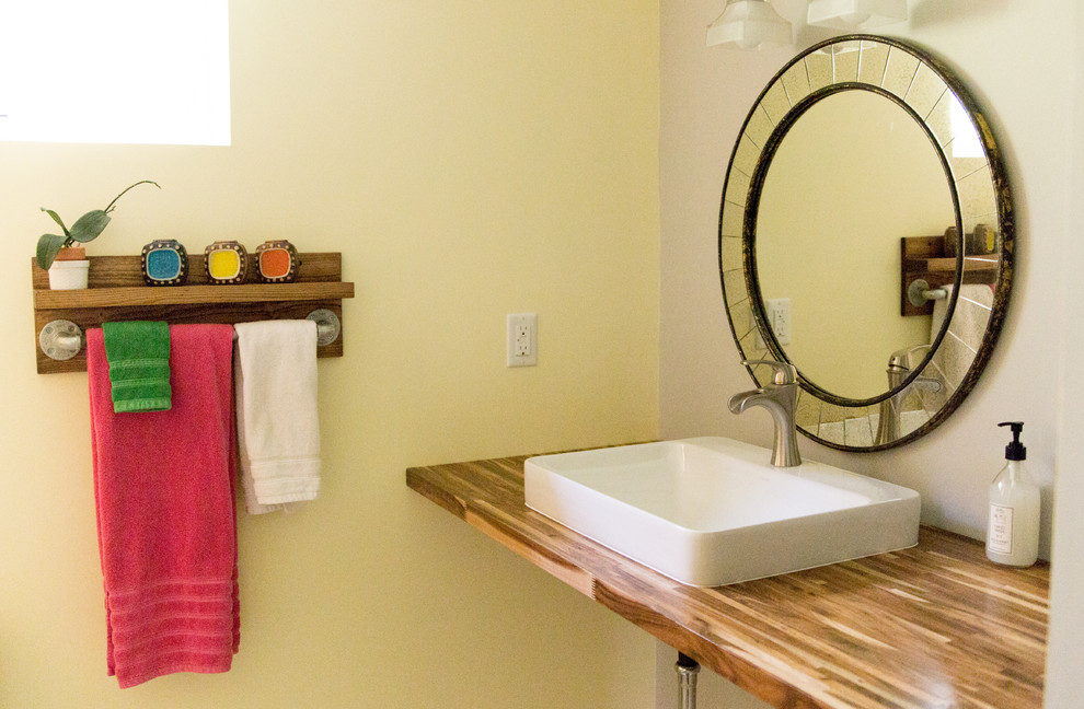 Eklektisk inredning av ett litet badrum med dusch, med skåp i ljust trä, ett fristående handfat och träbänkskiva