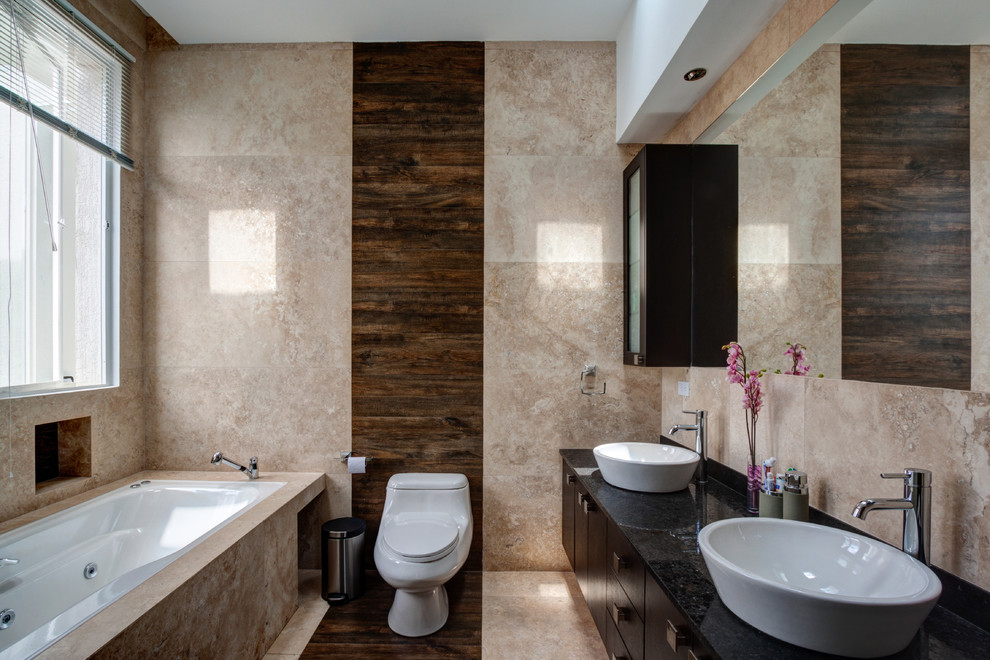 Стильный дизайн: ванная комната в современном стиле с настольной раковиной, плоскими фасадами, темными деревянными фасадами, накладной ванной и бежевой плиткой - последний тренд
