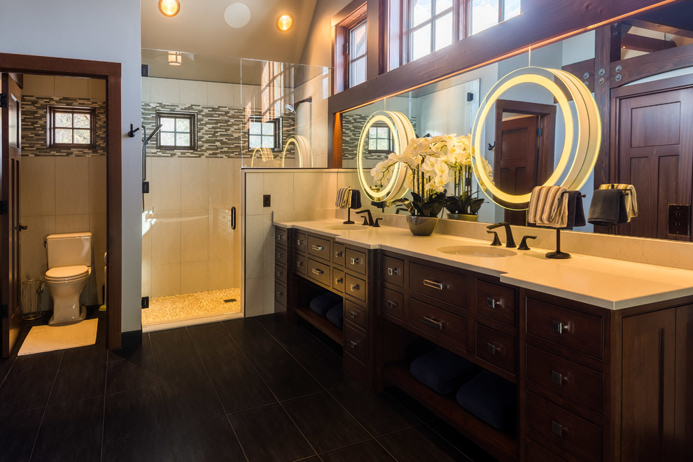 Modern inredning av ett mycket stort en-suite badrum, med luckor med profilerade fronter, skåp i mörkt trä, en öppen dusch, en toalettstol med separat cisternkåpa, grå kakel, porslinskakel, grå väggar, klinkergolv i keramik, ett undermonterad handfat, bänkskiva i kvartsit, svart golv och dusch med gångjärnsdörr