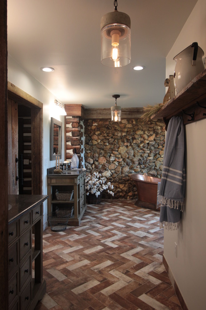 Bathroom - mid-sized country master beige tile and porcelain tile brick floor and multicolored floor bathroom idea in Atlanta with furniture-like cabinets, distressed cabinets, a one-piece toilet, white walls, an undermount sink, soapstone countertops and gray countertops