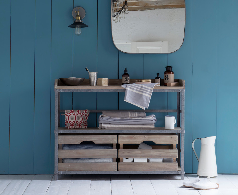 Modelo de cuarto de baño infantil de estilo de casa de campo con armarios abiertos, paredes azules, suelo de madera pintada y encimera de madera