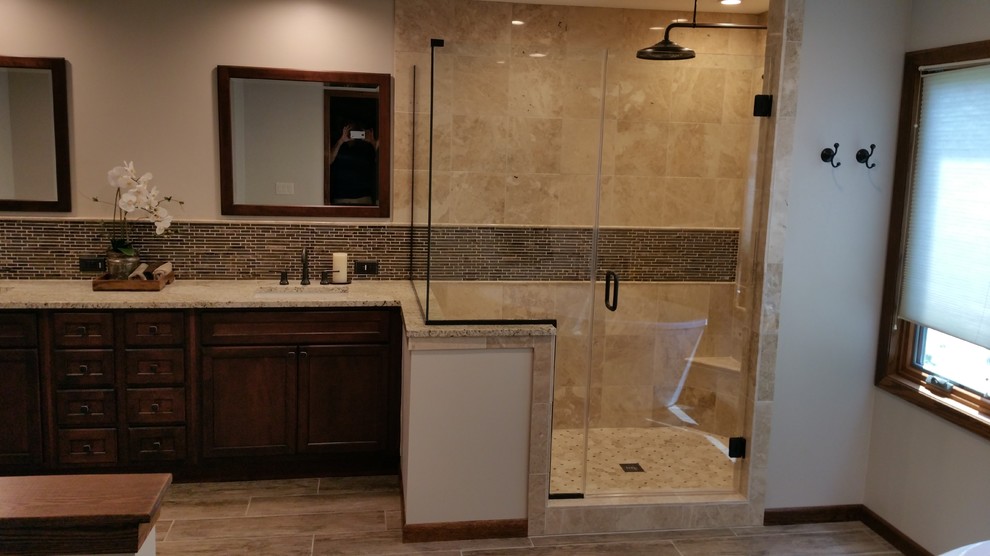 Cette photo montre une salle de bain principale chic en bois foncé avec un lavabo encastré, un placard avec porte à panneau encastré, une douche d'angle, un carrelage beige, des carreaux de céramique, un mur beige, un plan de toilette en granite et un sol en bois brun.