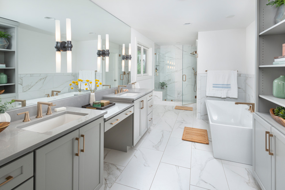 Cette image montre une salle de bain traditionnelle avec un placard à porte shaker, des portes de placard grises, une baignoire indépendante, un mur blanc, un lavabo encastré, un sol blanc, un plan de toilette gris et meuble double vasque.