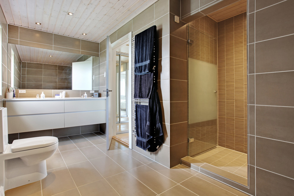 Nordisches Badezimmer mit beigen Schränken, Toilette mit Aufsatzspülkasten, braunen Fliesen, brauner Wandfarbe und beigem Boden in Kopenhagen