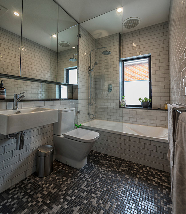 Стильный дизайн: ванная комната среднего размера в классическом стиле с фасадами с выступающей филенкой, ванной в нише, душем над ванной, раздельным унитазом, серой плиткой, плиткой кабанчик, полом из мозаичной плитки, подвесной раковиной, столешницей из плитки, серым полом и открытым душем - последний тренд