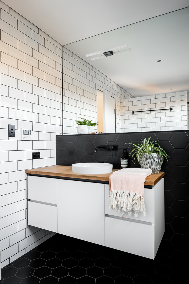 Idées déco pour une salle de bain scandinave avec un placard à porte plane, des portes de placard blanches, un mur blanc et un sol noir.