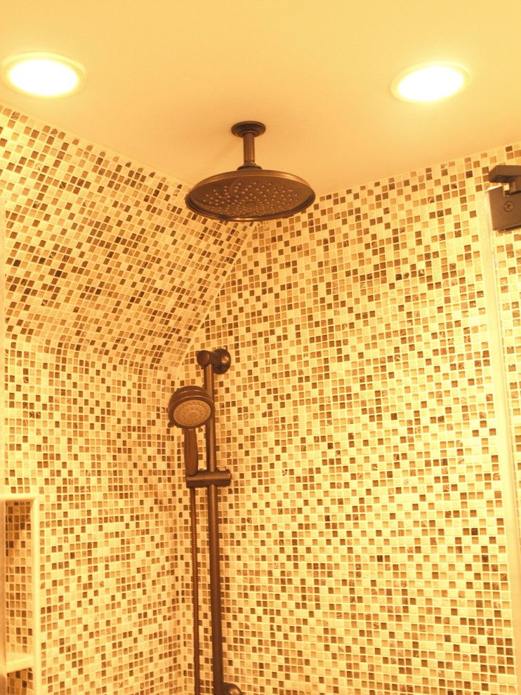 Corner shower - mid-sized mediterranean master multicolored tile and mosaic tile ceramic tile and beige floor corner shower idea in Newark with flat-panel cabinets, medium tone wood cabinets, a two-piece toilet, beige walls, an undermount sink, quartz countertops and a hinged shower door