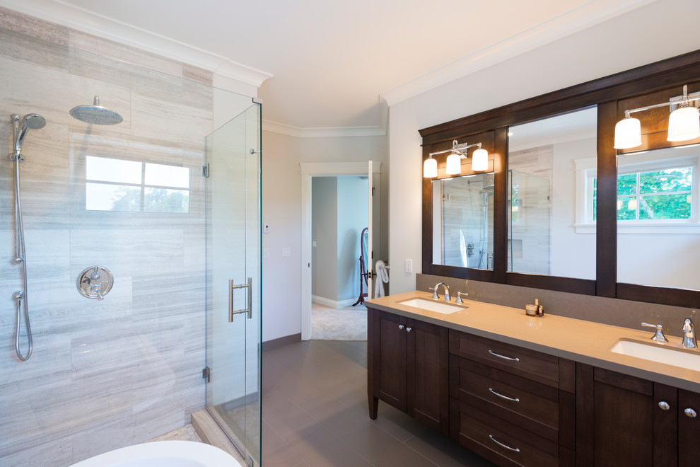 Photo of a large classic ensuite bathroom in Vancouver with a submerged sink, shaker cabinets, dark wood cabinets, engineered stone worktops, a freestanding bath, a corner shower, a two-piece toilet, grey tiles, porcelain tiles, grey walls and porcelain flooring.