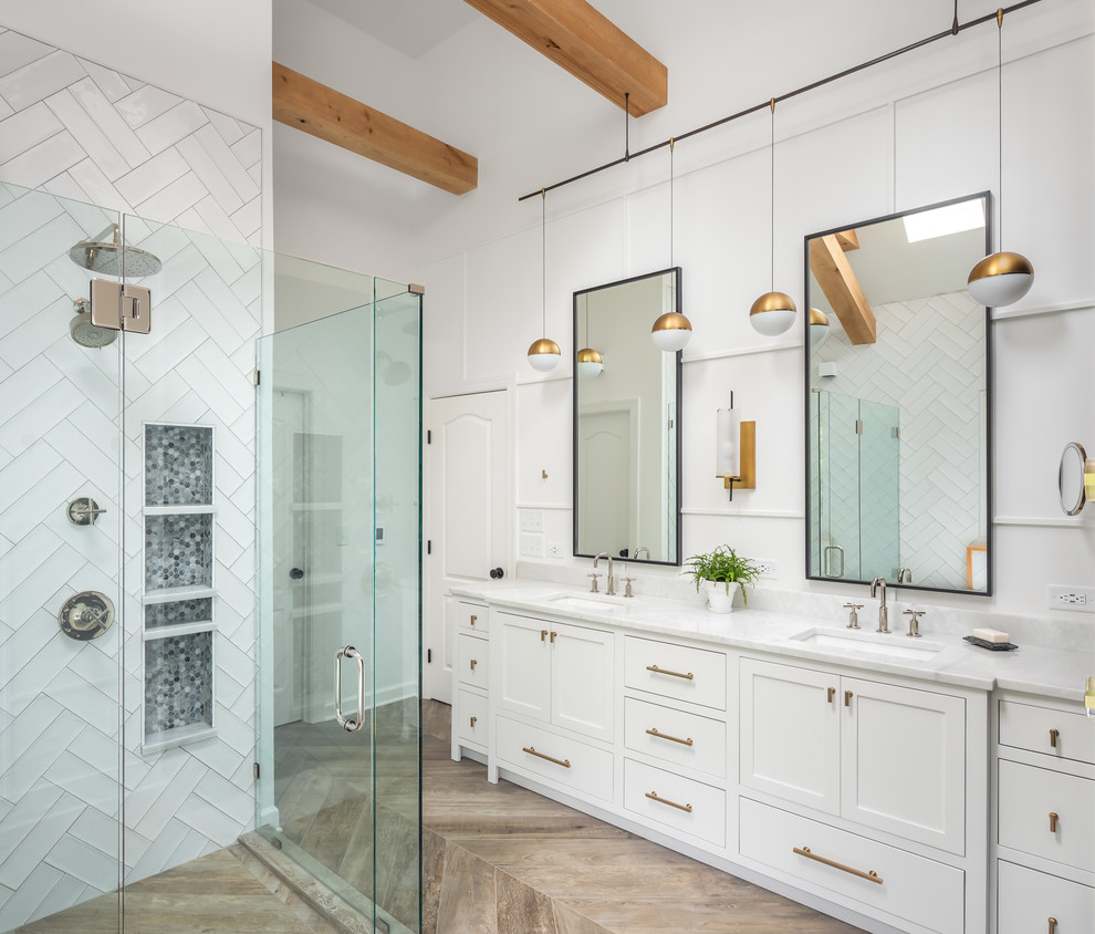 Bathroom - mid-sized farmhouse master white tile and ceramic tile porcelain tile and brown floor bathroom idea in Raleigh with recessed-panel cabinets, white cabinets, a two-piece toilet, white walls, an undermount sink, marble countertops, a hinged shower door and white countertops