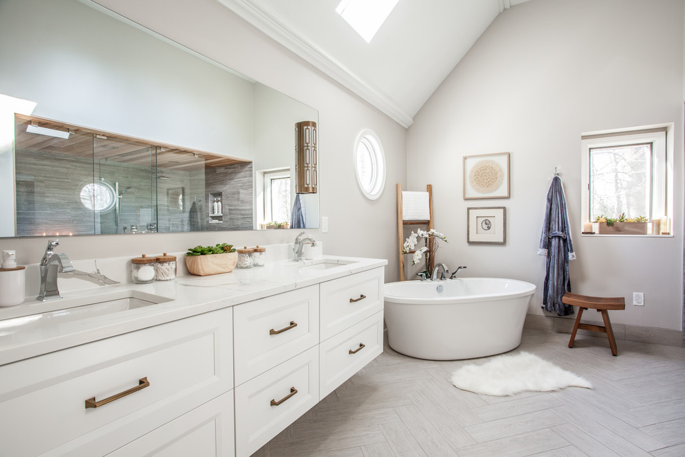 Foto på ett vintage vit badrum, med luckor med infälld panel, vita skåp, ett fristående badkar, beige väggar, ett undermonterad handfat och beiget golv