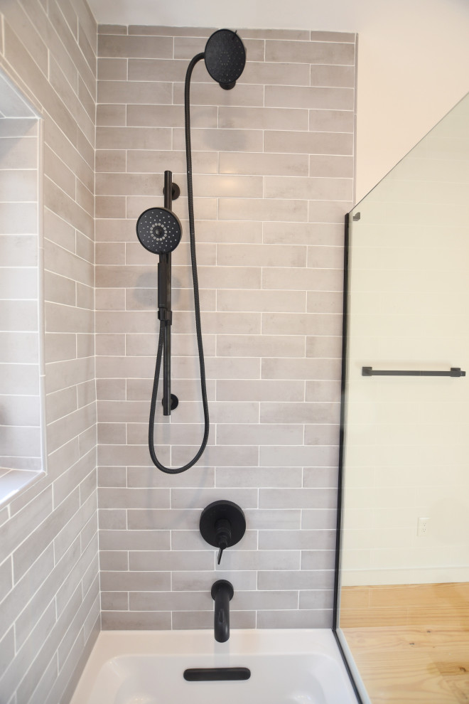 Medium sized midcentury ensuite bathroom in New York with open cabinets, black cabinets, a built-in bath, a shower/bath combination, a two-piece toilet, grey tiles, metro tiles, white walls, light hardwood flooring, a vessel sink, engineered stone worktops, an open shower and grey worktops.