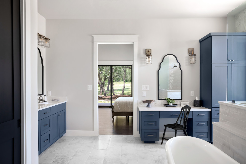 Идея дизайна: главная ванная комната в стиле кантри с фасадами с утопленной филенкой, синими фасадами, отдельно стоящей ванной, белыми стенами, белым полом, белой столешницей и тумбой под две раковины