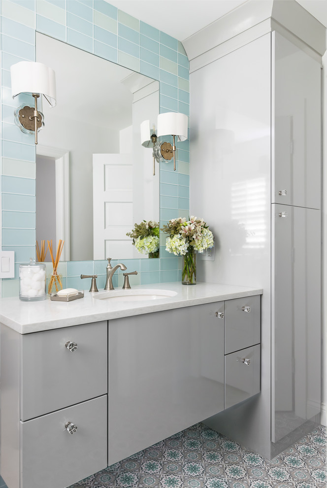 На фото: ванная комната среднего размера в стиле неоклассика (современная классика) с плоскими фасадами, серыми фасадами, стеклянной плиткой, врезной раковиной, разноцветным полом, белой столешницей и синей плиткой с