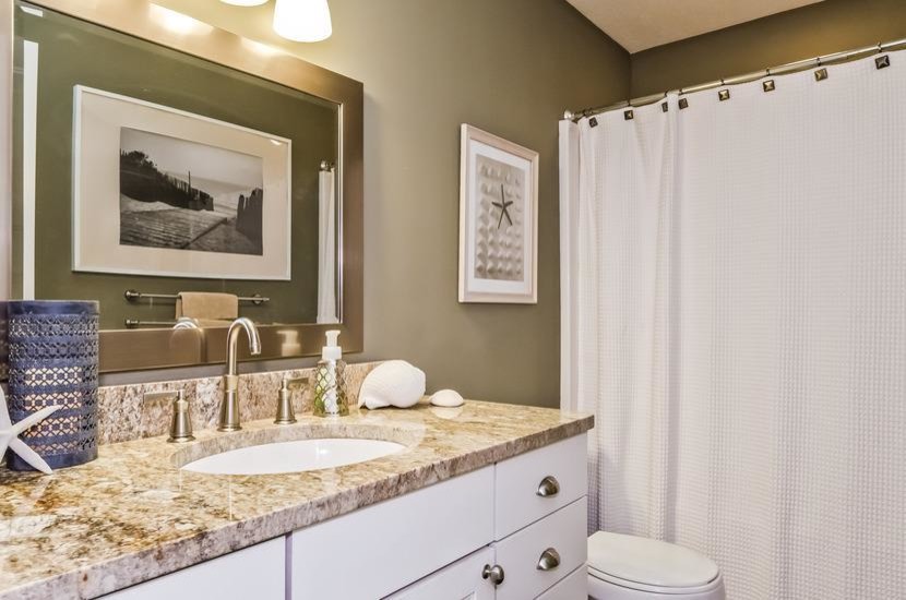 На фото: ванная комната среднего размера в морском стиле с врезной раковиной, плоскими фасадами, белыми фасадами, столешницей из гранита, ванной в нише, душем над ванной, раздельным унитазом и зелеными стенами с