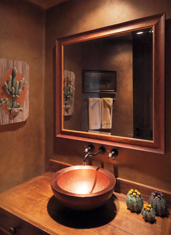 Modelo de cuarto de baño principal de estilo americano grande con armarios con paneles lisos, puertas de armario de madera oscura, paredes marrones, lavabo sobreencimera y encimera de madera