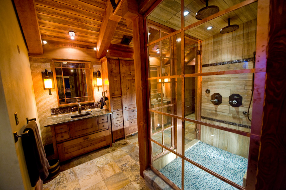 Aménagement d'une salle de bain principale montagne en bois brun avec un lavabo encastré, un placard en trompe-l'oeil, un plan de toilette en granite, une douche double, un mur beige et un sol en travertin.
