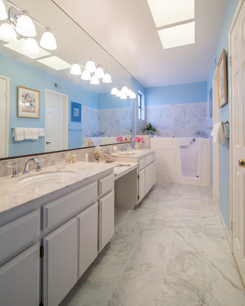 Idée de décoration pour une salle de bain principale minimaliste de taille moyenne avec un lavabo encastré, un placard avec porte à panneau surélevé, des portes de placard blanches, un plan de toilette en marbre, une baignoire indépendante, WC à poser, un carrelage blanc, des carreaux de céramique, un mur bleu et un sol en carrelage de céramique.