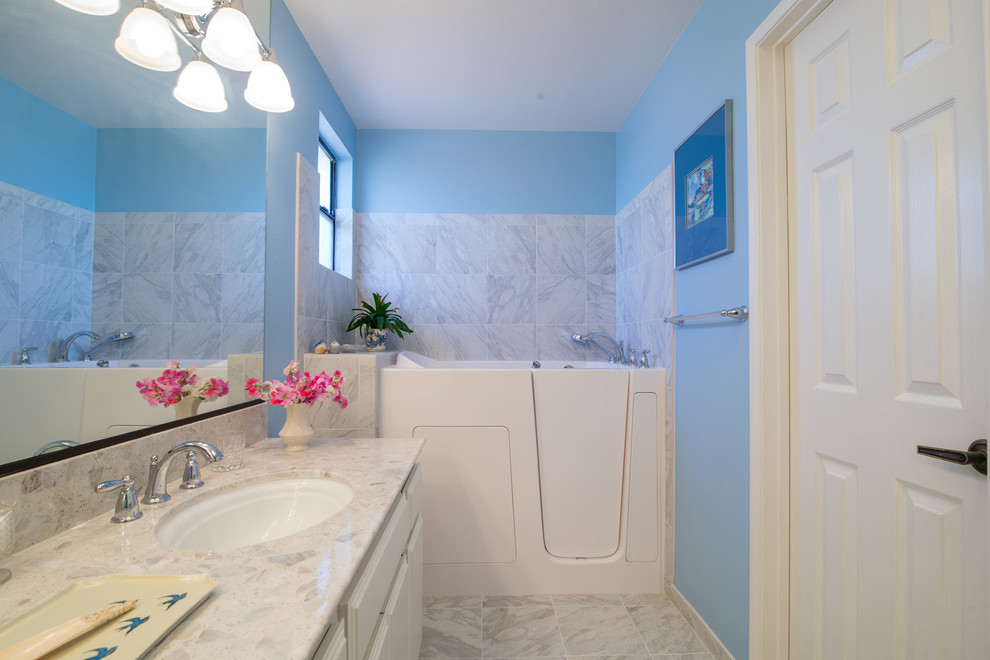 Medium sized modern ensuite bathroom in San Diego with a submerged sink, raised-panel cabinets, white cabinets, marble worktops, a freestanding bath, a one-piece toilet, white tiles, ceramic tiles, blue walls and ceramic flooring.