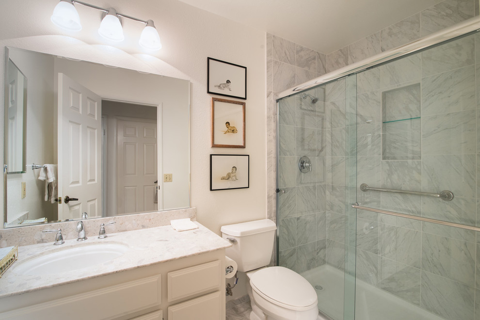 Photo of a medium sized modern ensuite bathroom in San Diego with a submerged sink, raised-panel cabinets, white cabinets, marble worktops, a freestanding bath, a one-piece toilet, white tiles, ceramic tiles, blue walls and ceramic flooring.