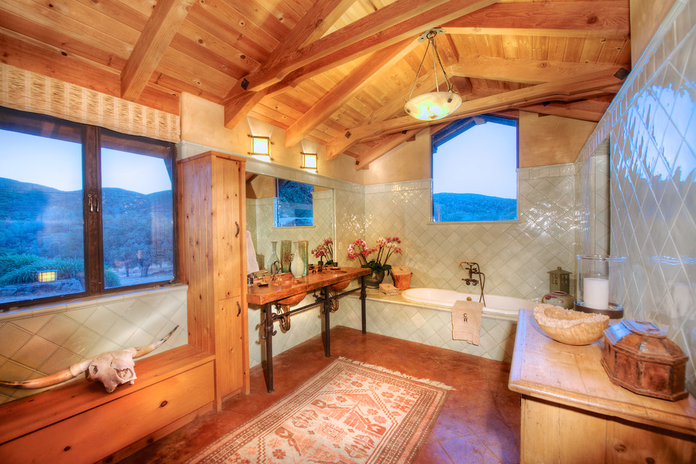 Amerikansk inredning av ett stort en-suite badrum, med ett väggmonterat handfat, möbel-liknande, skåp i ljust trä, ett platsbyggt badkar, grön kakel, keramikplattor, beige väggar och klinkergolv i terrakotta