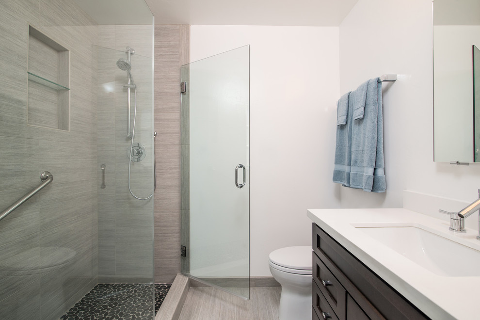Inspiration pour une salle de bain minimaliste en bois foncé de taille moyenne avec un lavabo encastré, un placard avec porte à panneau encastré, WC à poser, un carrelage gris, des carreaux de céramique, un mur blanc et un sol en carrelage de céramique.