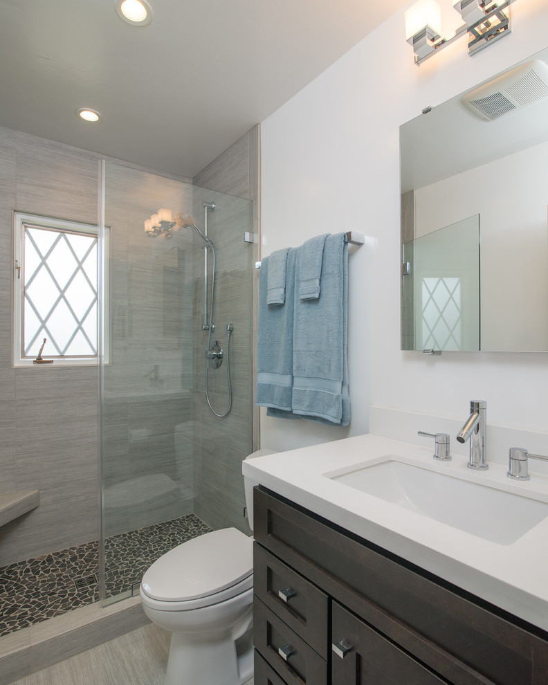Modelo de cuarto de baño tradicional renovado con lavabo bajoencimera, armarios estilo shaker, puertas de armario de madera en tonos medios, ducha empotrada, baldosas y/o azulejos grises y paredes blancas