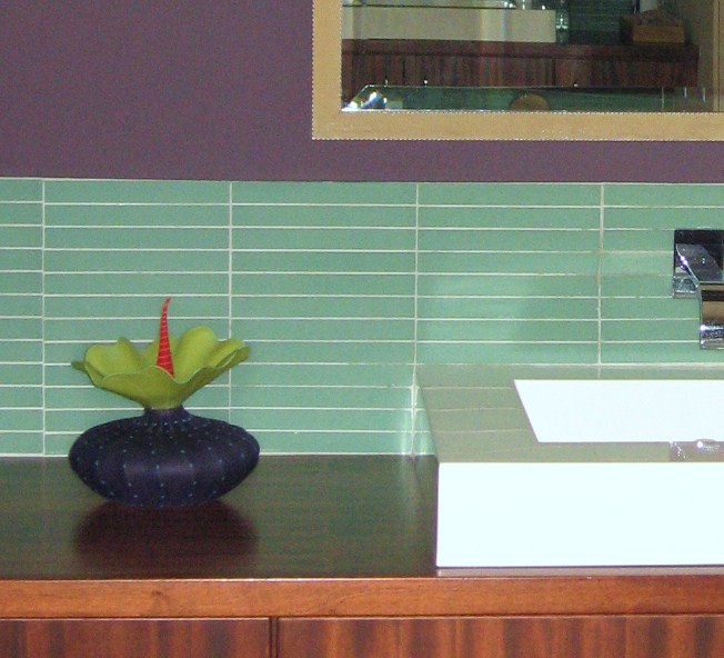 Идея дизайна: ванная комната в современном стиле с плоскими фасадами, фасадами цвета дерева среднего тона, зеленой плиткой, стеклянной плиткой, фиолетовыми стенами, настольной раковиной, столешницей из дерева и коричневой столешницей