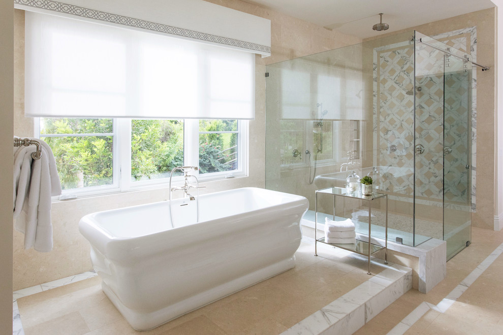 Идея дизайна: большая главная ванная комната в стиле неоклассика (современная классика) с отдельно стоящей ванной, душем без бортиков, бежевой плиткой, плиткой из известняка, полом из известняка, бежевым полом и душем с раздвижными дверями
