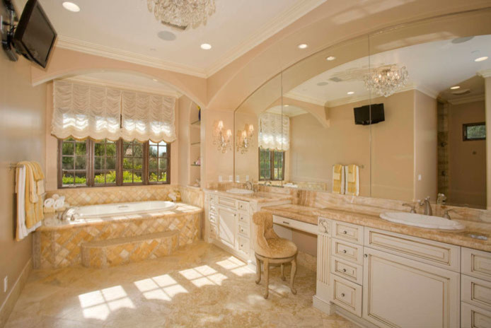 Medium sized mediterranean ensuite bathroom in San Diego with freestanding cabinets, distressed cabinets, a two-piece toilet, beige tiles, stone tiles, beige walls, limestone flooring, a vessel sink, wooden worktops and an alcove bath.