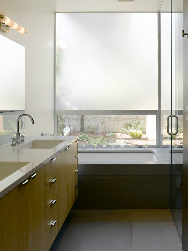 Réalisation d'une douche en alcôve minimaliste avec une baignoire encastrée, un mur blanc, sol en béton ciré, un lavabo encastré, un sol gris et une cabine de douche à porte battante.