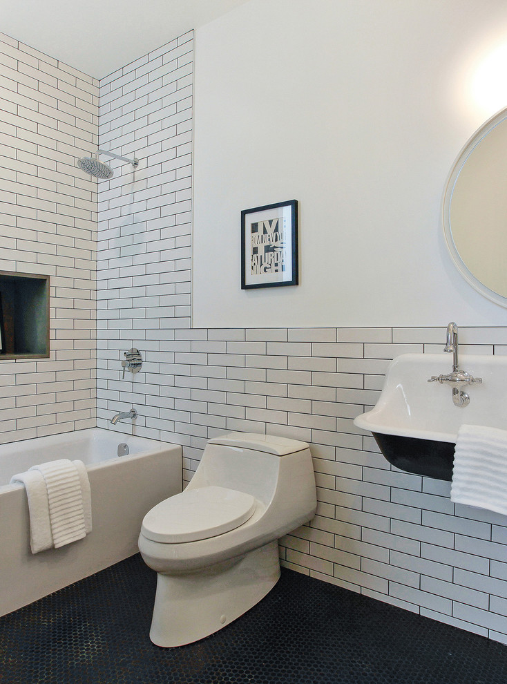 На фото: детская ванная комната среднего размера в стиле модернизм с ванной в нише, душем над ванной, унитазом-моноблоком, белой плиткой, керамической плиткой, белыми стенами, полом из керамической плитки и подвесной раковиной