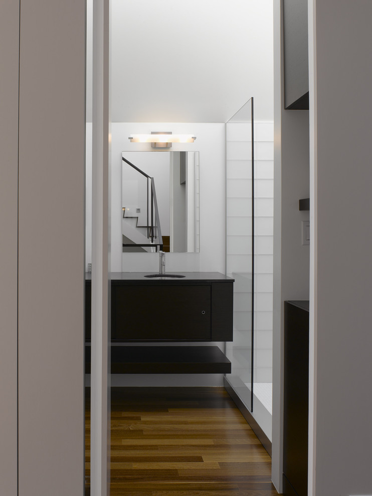 This is an example of a medium sized modern shower room bathroom in San Francisco with flat-panel cabinets, black cabinets, an alcove shower, white tiles, glass tiles, white walls, dark hardwood flooring, a submerged sink, brown floors and an open shower.