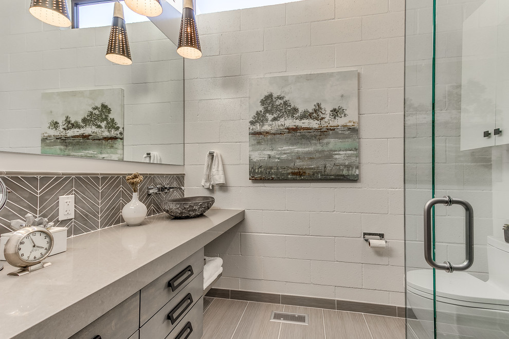 Cette photo montre une salle de bain tendance avec un placard à porte plane, des portes de placard grises, une douche d'angle, WC à poser, un mur blanc et un plan de toilette gris.