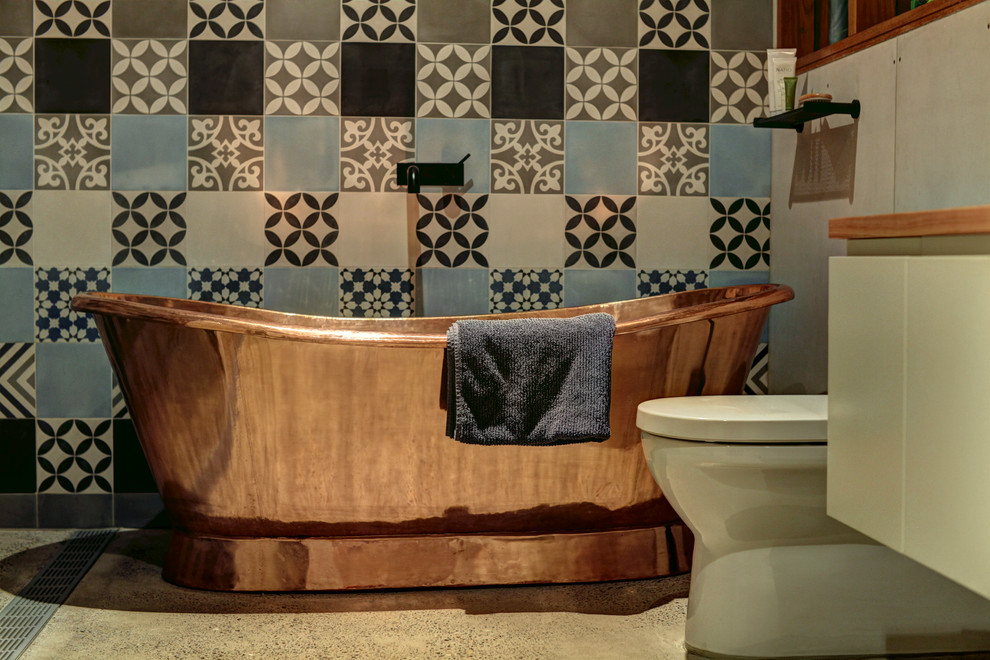 Idée de décoration pour une salle de bain principale bohème en bois clair de taille moyenne avec une baignoire indépendante, une douche ouverte, sol en béton ciré, WC à poser, un carrelage bleu, des carreaux de béton, un mur bleu, une vasque et un plan de toilette en bois.