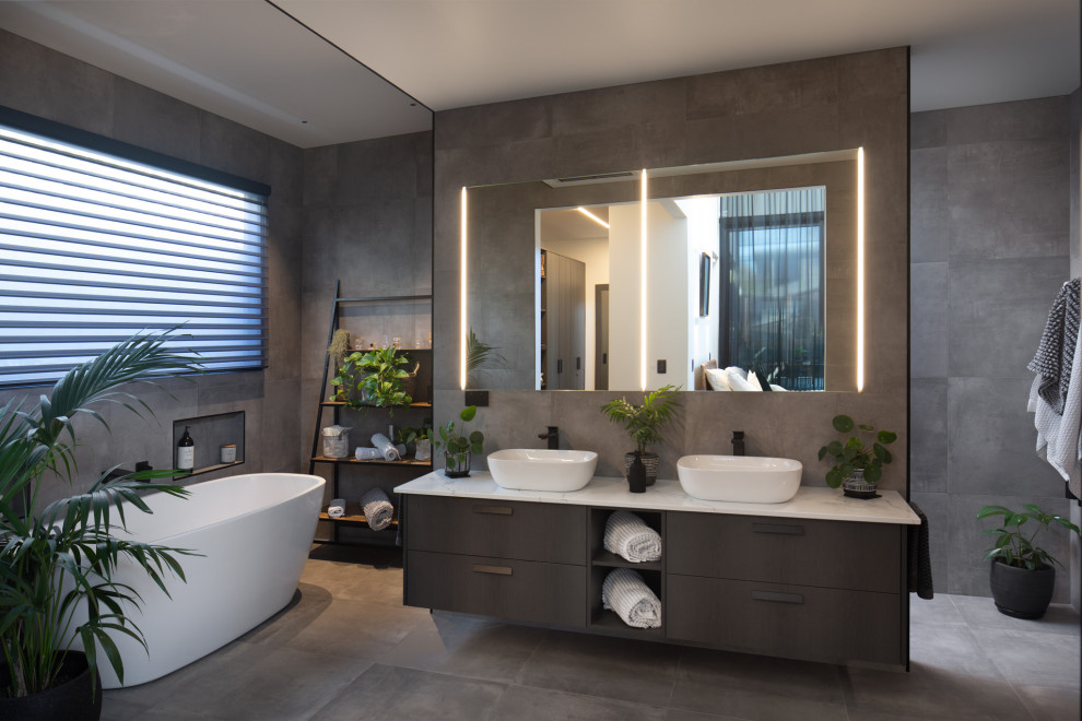 Exempel på ett stort modernt vit vitt badrum med dusch, med släta luckor, bruna skåp, ett fristående badkar, grå kakel, ett fristående handfat och grått golv