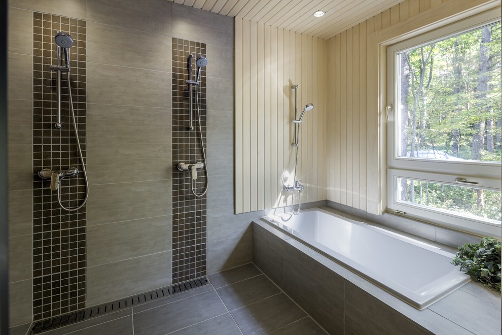 Foto di una grande stanza da bagno design con doccia doppia, piastrelle grigie, piastrelle in pietra, pareti grigie e vasca da incasso