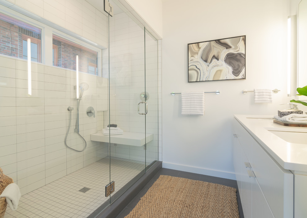 Medium sized modern ensuite bathroom in Seattle with flat-panel cabinets, white cabinets, an alcove shower, a one-piece toilet, white tiles, ceramic tiles, white walls, ceramic flooring, a submerged sink, solid surface worktops, grey floors, a hinged door and white worktops.