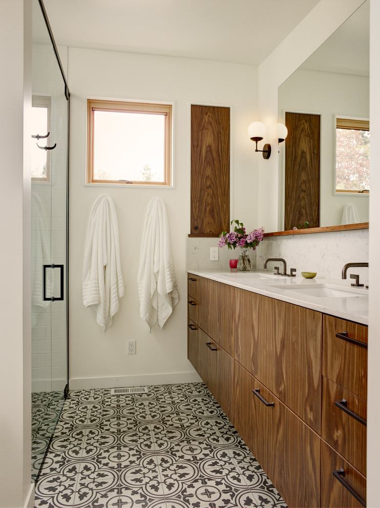 Foto på ett funkis vit badrum, med släta luckor, skåp i mellenmörkt trä, en kantlös dusch, vit kakel, vita väggar, ett undermonterad handfat, flerfärgat golv och dusch med gångjärnsdörr