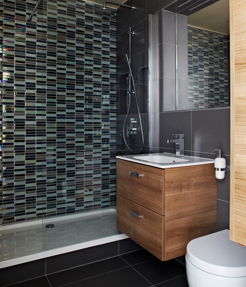 Idée de décoration pour une salle de bain design en bois foncé de taille moyenne avec un lavabo intégré, un placard en trompe-l'oeil, une douche ouverte, WC suspendus, un carrelage gris, des carreaux de céramique, un mur gris et un sol en carrelage de céramique.