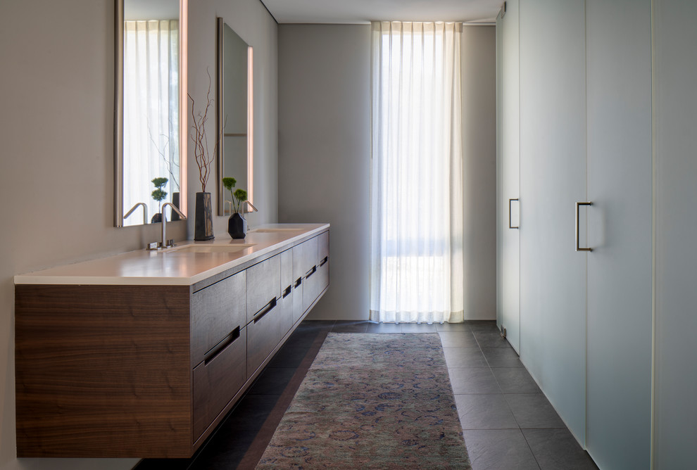 Immagine di una stanza da bagno design con ante lisce, ante in legno scuro, pareti bianche, lavabo sottopiano, pavimento grigio e top bianco