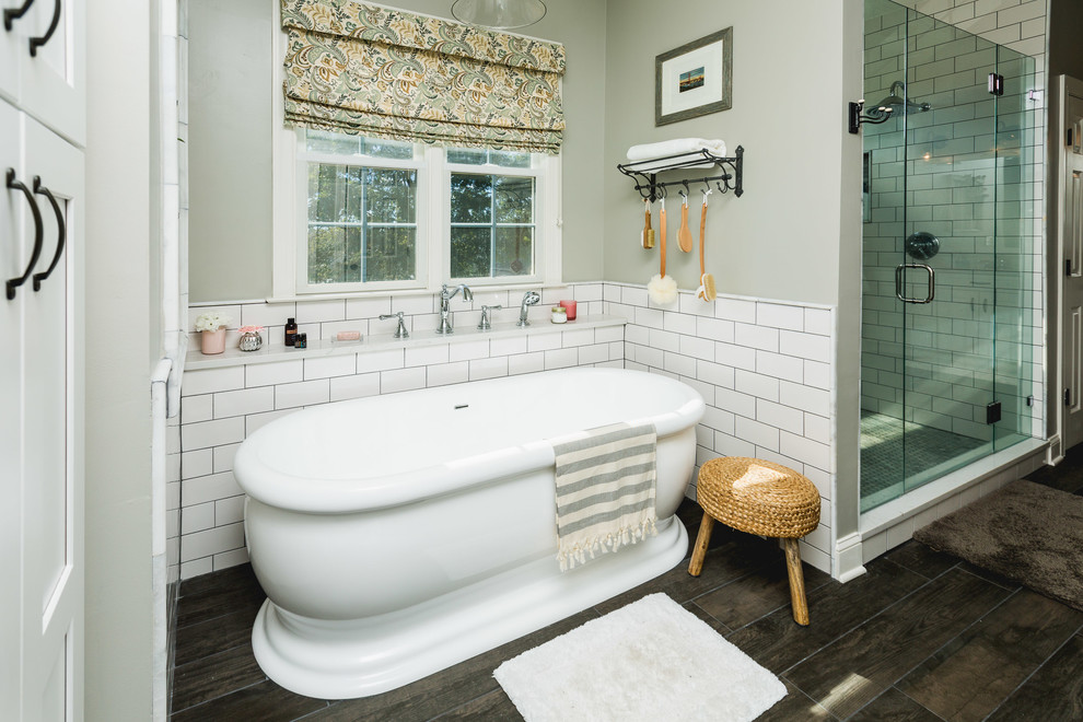This is an example of a large classic ensuite bathroom in DC Metro with shaker cabinets, white cabinets, a freestanding bath, an alcove shower, white tiles, metro tiles, grey walls, dark hardwood flooring, a submerged sink, engineered stone worktops, brown floors, a hinged door and grey worktops.