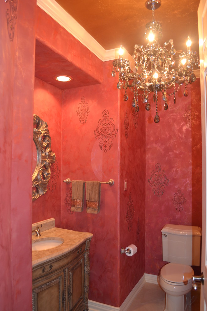 Modelo de cuarto de baño clásico renovado de tamaño medio con armarios tipo mueble, puertas de armario de madera oscura, sanitario de dos piezas, baldosas y/o azulejos beige, baldosas y/o azulejos de piedra, paredes rojas, suelo de mármol y lavabo bajoencimera